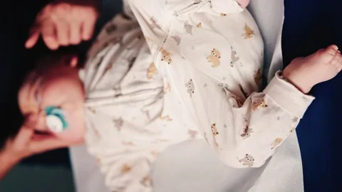 Overhead view of a caregiver gently handling an infant during a medical or Stock Footage 325701341