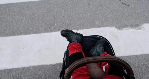 An overhead view of a child in a stroller crossing a pedestrian strip crossing. Stock Footage 274093136