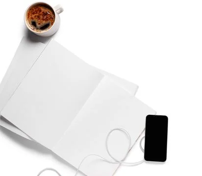 Overhead view of coffee cup, blank notebook, and smartphone with earbuds on w Stock Photos