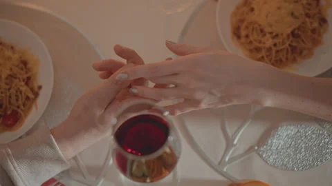 Overhead view of couple holding hands across restaurant table during warm dinner Stock Footage 346643519