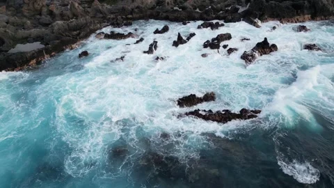 Overhead View of Crashing Waves and Turquoise Blue Ocean Water on Rugged Rocks Stock Footage 320604616