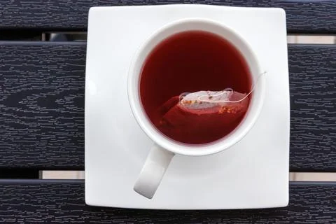 Overhead view of a cup of red fruit tea with a teabag in a white cup on a s.. Stock Photos