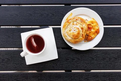 Overhead view of a cup of red fruit tea and a white plate with sweet burek .. Фото
