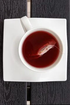Overhead view of a cup of red fruit tea with a teabag in a white cup on a s.. Stock Photos