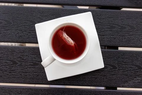 Overhead view of a cup of red fruit tea with a teabag in a white cup on a s.. Stock Photos