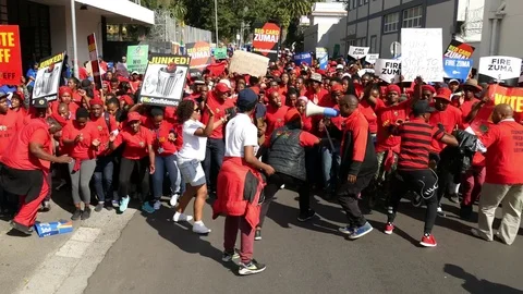 Overhead view of dancing EFF protesters dressed in red with placards with "Zuma  Vidéo 78641926