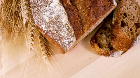 Overhead view of dark bread cut into slices on a wooden board with breadcrumbs Stock Footage 202047696