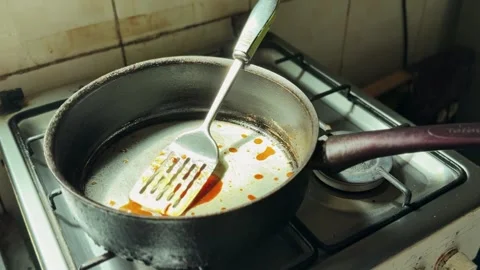 Overhead View of Dirty Frying Pan with Metal Spatula on Gas Stove After Cooking Stockbeeldmateriaal 333438701