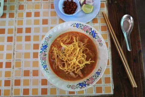 Overhead view of dish called Khao Soi with chopsticks, lime and chili paste. Стоковые фото
