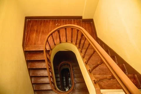 Overhead view down a warm-toned wooden spiral staircase with an oval stairw.. Stock Photos