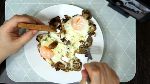 Overhead view eating frying eggs watching videos on the phone Stock Footage 254398174
