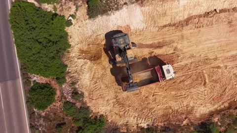 Overhead view of an excavator loading soil into a dump truck at an active Vidéo 336742754