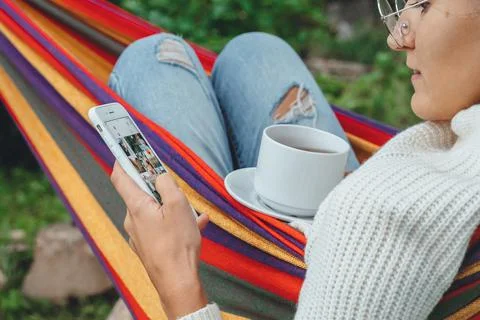 Overhead view Fall autumn millennial woman using smart phone relaxing on hamm Stock Photos