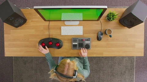 Overhead View Of Female Video Editor Working At Computer With Green Screen In Stock Footage 168892291