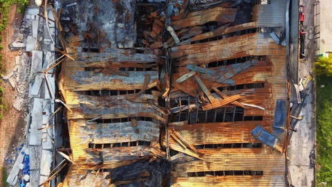 Overhead view of fire-ravaged industrial building with collapsed roof, charred Stock Footage 334161575