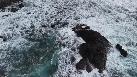 Overhead View of Foamy Ocean Surf Around Dark Rocks Stock Footage 345576440