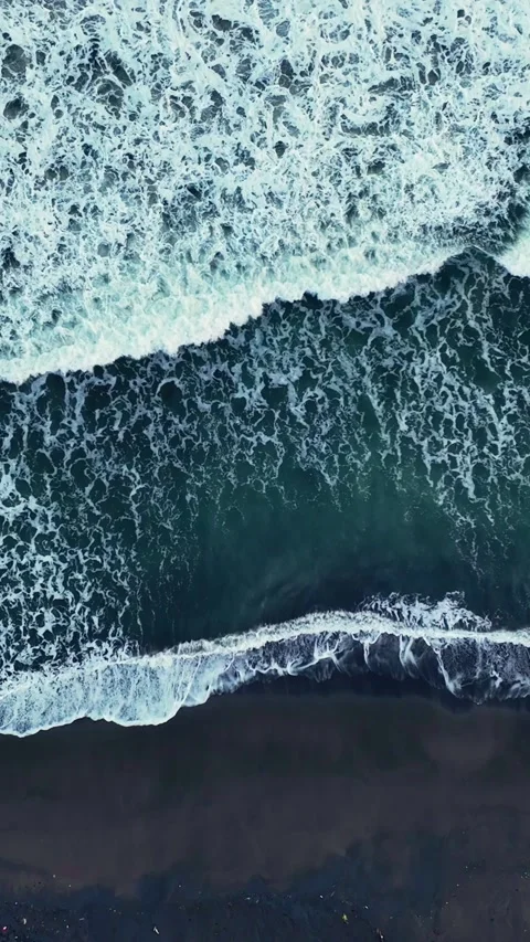 Overhead view of foamy waves on black sand Stock Footage 335432773