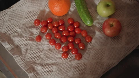 Overhead view of fresh cherry tomatoes, mandarin, cucumber, and apples scattered Stock Footage 346658248