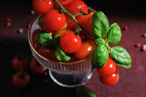Overhead view of fresh cherry tomatoes and basil in crystal bowl Foto stock