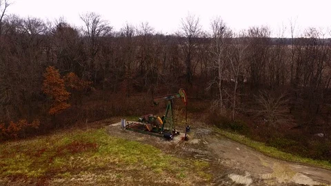 An overhead view of a functioning pump jack with winter trees in the 動画素材 101631265