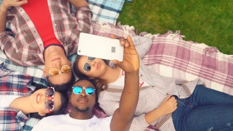 Overhead view of group taking selfie lying on plaid outdoors Stock Footage 127912102
