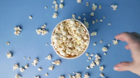 Overhead View of Hand Grabbing Popcorn from Bowl on Blue Background with Sc.. Stock Footage 304801921