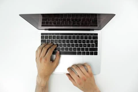 Overhead view of the hands of a person using his laptop on a white table. Stock Photos