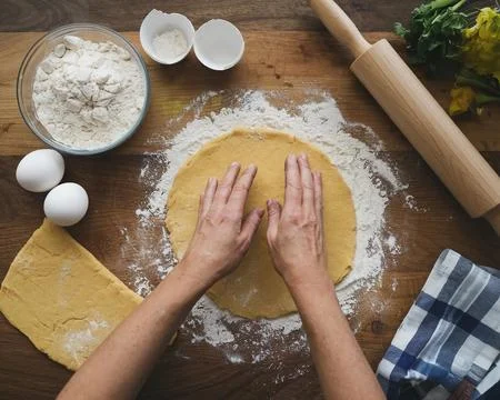 Overhead view of a hands preparing dough with flour, eggs, and rolling pin Stock Photos
