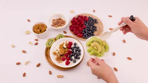 Overhead View of Hands Preparing Greek Yogurt Bowl with Fresh Fruit Stock Footage 337768576