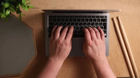 Overhead view of hands typing on a laptop keyboard next to drumsticks Vidéo 341737461