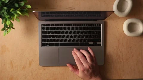 Overhead view of hands typing on a laptop with headphones and plant on desk Vidéo 341737623