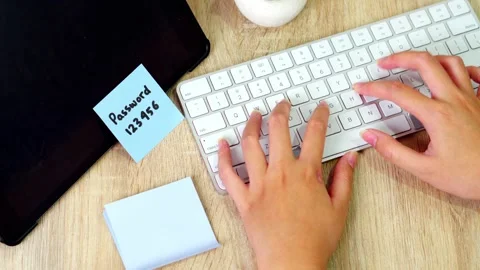 Overhead view of hands typing on white keyboard with blue sticky note showing Stock Footage 330888806