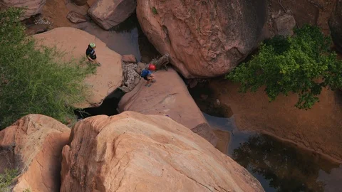 Overhead view of hikers hopping from boulder to boulder on hike Stock Footage 128777515