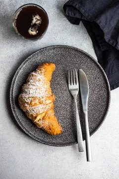 Overhead view of an Iced coffee drink with a fresh vanilla croissant on a table Stock Photos