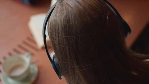Overhead view of lady writing with coffee cup beside and novel dancing to music Stock Footage 310752274