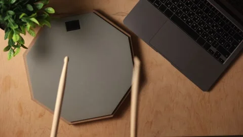 Overhead view of a laptop and drum practice pad on a wooden desk Stockbeeldmateriaal 341737705