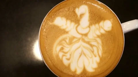 An overhead view of latte with intricate latte art, resting on cafe table. Stock-Footage 334648793