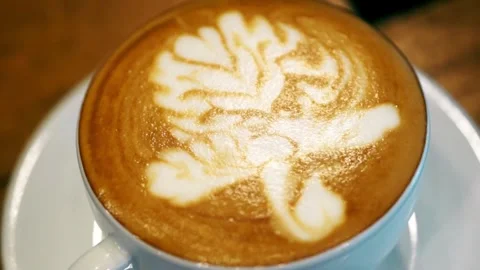 An overhead view of latte with intricate latte art, resting on cafe table. Stock-Footage 334648797