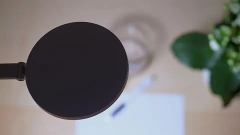 Overhead view of a lit desk lamp standing above a worktable with a paper on it 動画素材 170594225
