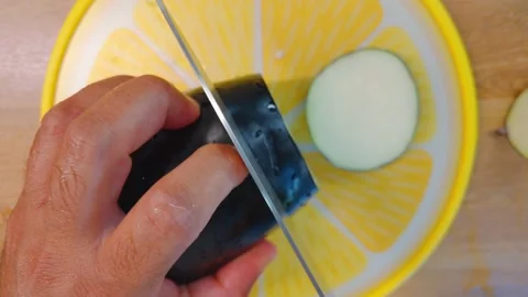 Overhead view of male hands slicing a fresh purple aubergine with a sharp knife Stock Footage 342076332