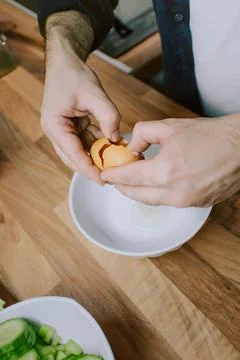 Overhead view of man cracking open an egg to prepare breakfast in the morning Stock Photos