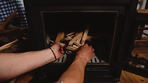 Overhead view of a man loading firewood into a wood burning stove in a rustic fa Stock Footage 266821550