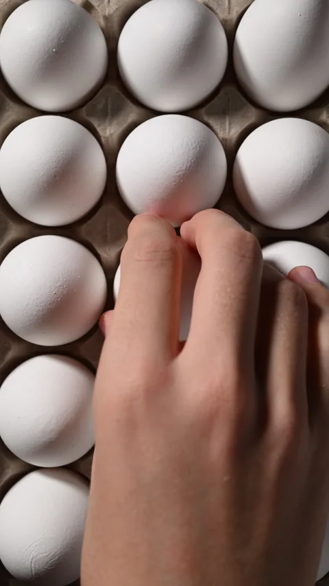 Overhead view of a man selecting a white egg from a box for his recipe. 動画素材 319493736