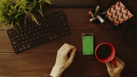 Overhead view of man using smartphone with green screen and drinking tea Stock Footage 81174716