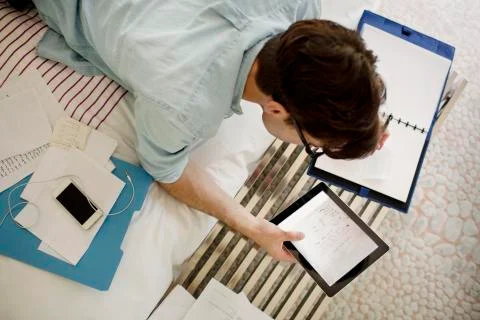 Overhead view of man using tablet computer while working on bed at home Foto stock