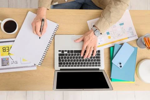 Overhead view of man working on laptop and taking notes, creative design proc Stock Photos