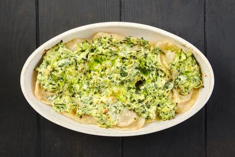 Overhead view of meat dumplings with spinach and cheese sauce baked in oven Foto stock
