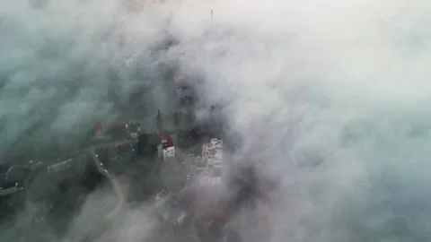 Overhead View of Mountain Village Emerging Through Dense Fog Above Cloud Stock Footage 333423335