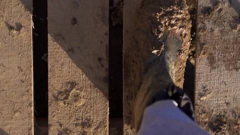 An overhead view of the muddy boots striding across the wooden deck. a builder Stock Footage 158902366