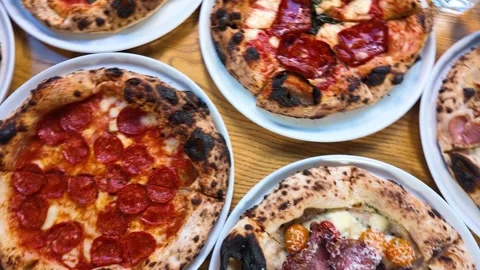 Overhead View of Multiple Neapolitan Pizzas on a Wooden Restaurant Table Stock Footage 338321330